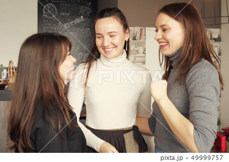Three women friends are hugging together greeting. Friendly meeting in cafe. Three women friends are hugging together greeting. Friendly meeting in cafe. 49999757