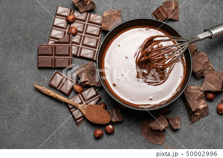 ceramic bowl of chocolate cream or melted chocolate and pieces of chocolate on dark concrete 50002996