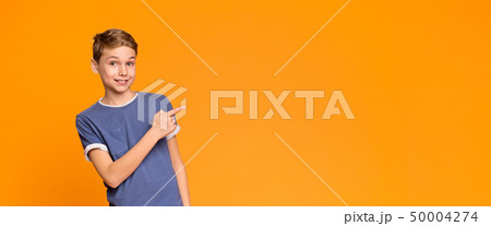 Emotional teen boy pointing aside at empty space 50004274