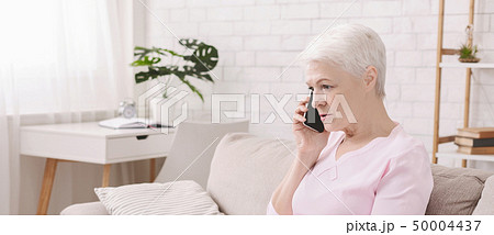 Unhappy worried senior woman talking on phone 50004437