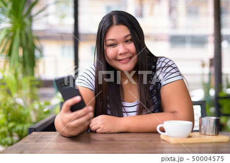 Beautiful overweight Asian woman relaxing at the coffee shop 50004575