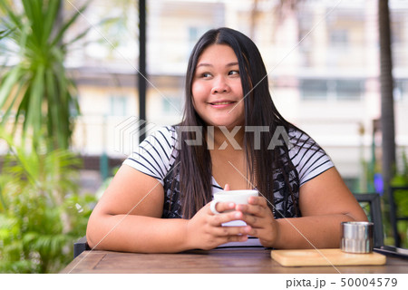 Beautiful overweight Asian woman relaxing at the coffee shop 50004579