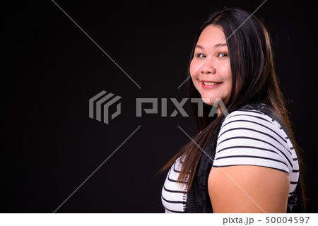 Beautiful overweight Asian woman against black background Beautiful overweight Asian woman against black background 50004597
