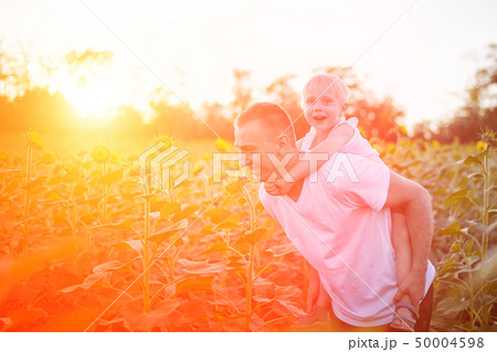 Happy father with son on back walking on a green 50004598