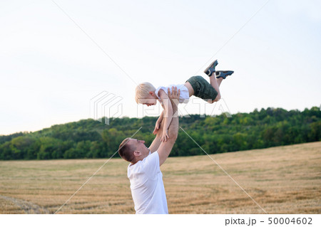 Happy father throws up a little blond boy on a Happy father throws up a little blond boy on a 50004602