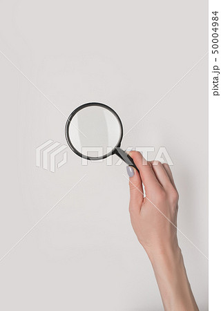 Female hand holding magnifier isolate on light 50004984