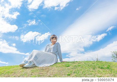 青空の下 芝生の丘の上で  さわやかなアラフォー女性  50005074