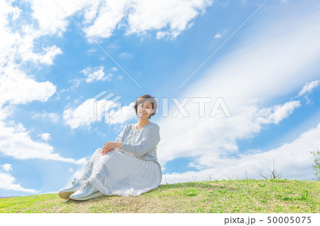 青空の下 芝生の丘の上で  さわやかなアラフォー女性  50005075