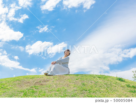 青空の下 芝生の丘の上で  さわやかなアラフォー女性  50005084