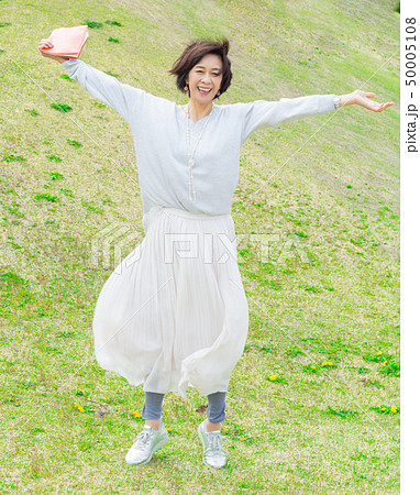 青空の下 芝生の上で  本を持つ さわやかなアラフォー女性  50005108