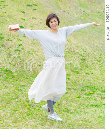青空の下 芝生の上で 本を持つ さわやかなアラフォー女性 青空の下 芝生の上で 本を持つ さわやかなアラフォー女性 50005110