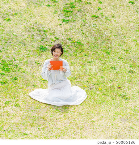 青空の下 芝生の上で 本を持つ さわやかなアラフォー女性 青空の下 芝生の上で 本を持つ さわやかなアラフォー女性 50005136