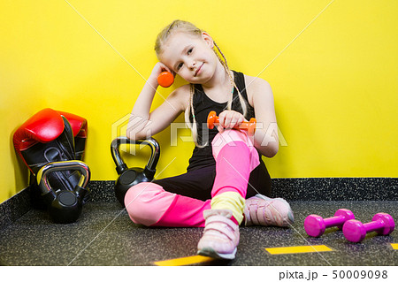 Theme sports and health children. Little funny child Caucasian girl with pigtails, sits resting 50009098