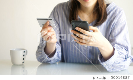 スマホとカードを見る女性 50014887