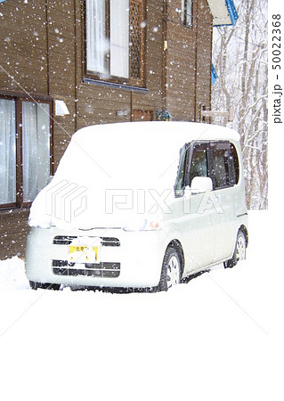 雪国の田舎暮らし 雪降り 雪をかぶり自宅前に駐車している軽自動車の写真素材