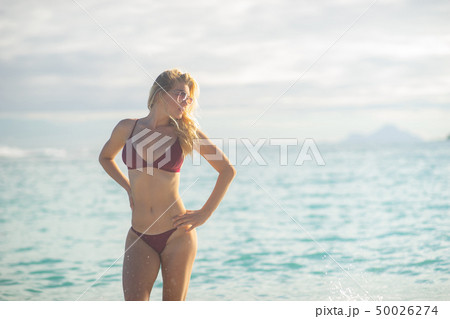 Attractive blonde girl walking on the beach, fit sporty healthy sexy body in bikini, woman enjoys 50026274