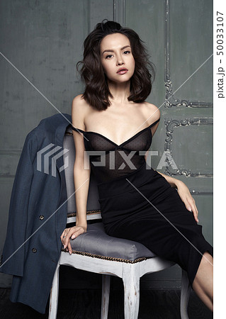 Woman in evening dress sitting on chair Woman in evening dress sitting on chair 50033107
