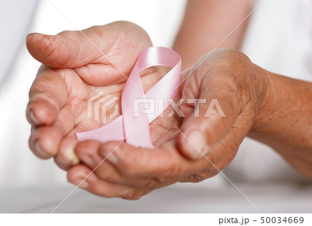 Elder woman hands holding pink breast cancer awareness ribbon Elder woman hands holding pink breast cancer awareness ribbon 50034669