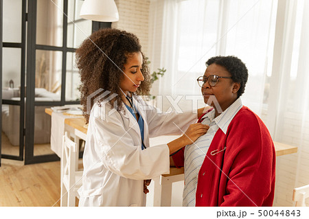 Nurse in white jacket using stethophone listening to heart beat 50044843