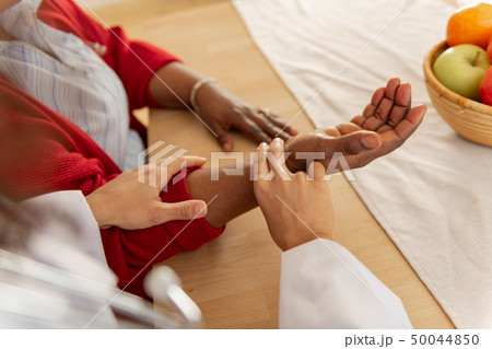 Nurse wearing white jacket checking the pulse for woman 50044850
