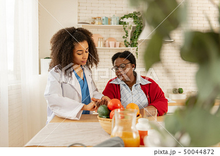 Medical attendant coming to kitchen and measuring pulse for patient Medical attendant coming to kitchen and measuring pulse for patient 50044872
