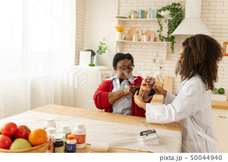 Curly dark-haired nurse measuring the blood pressure of aged woman Curly dark-haired nurse measuring the blood pressure of aged woman 50044940