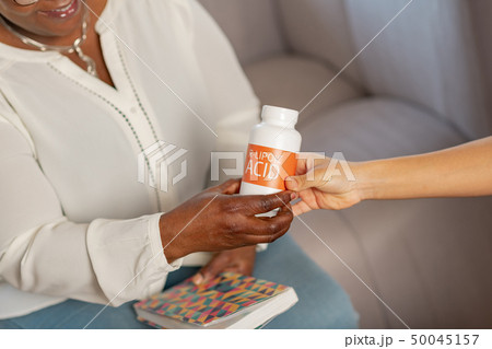 Aged patient of nursing house taking supplements from nurse 50045157