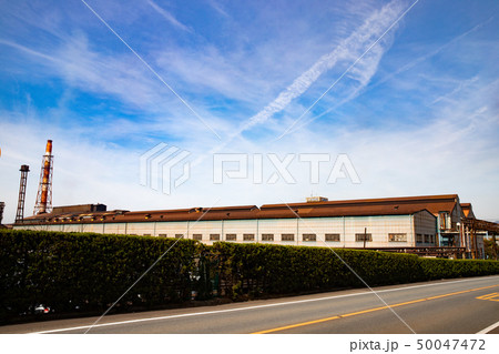 青空と製鉄所内の工場建屋と煙突 50047472