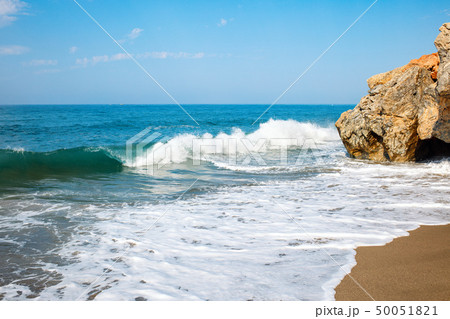 Sandy beach and soft blue ocean wave with white foam. 50051821