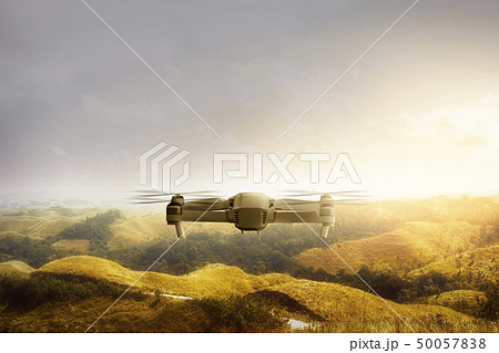 White drone with camera flying above green hills 50057838