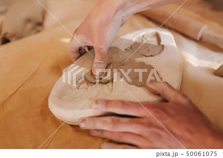 Hands of potter fill the form with a ceramic in the shape of a butterfly. Close up of hands 50061075
