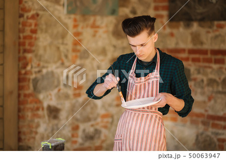 Earthenware in potter's hand. Artist making ornament on ceramic product. Male potter working 50063947