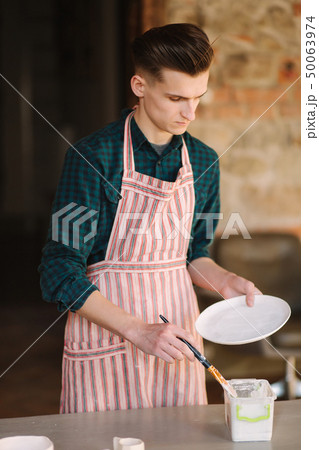 Earthenware in potter's hand. Artist making ornament on ceramic product. Male potter working 50063974