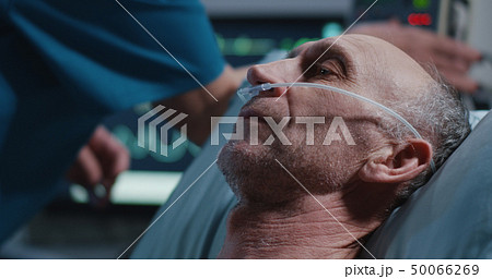 Nurse placing nasal cannula into patients nose 50066269