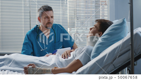 Male doctor visiting teenager patient in hospital 50067658