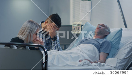Man lying in hospital among family 50067994