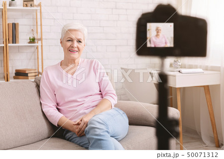 Friendly senior woman vlogger sitting on sofa dating online Friendly senior woman vlogger sitting on sofa dating online 50071312