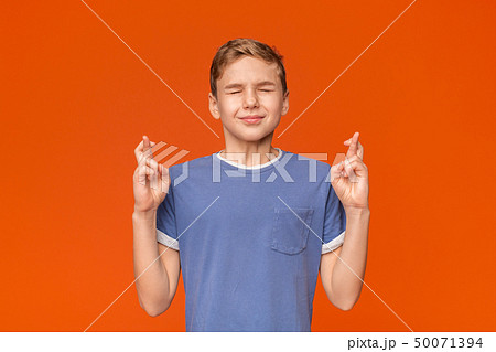Teenager crossing fingers wishing, praying for miracle 50071394