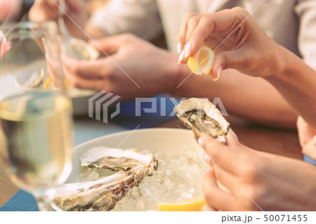 Gentle lady carrying piece of lemon and squeezing it on fresh oyster Gentle lady carrying piece of lemon and squeezing it on fresh oyster 50071455