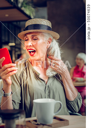 Joyful blonde woman touching her pony tail 50074639