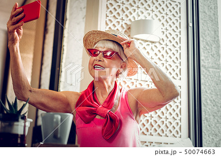 Cheerful nice elderly woman taking great photos 50074663