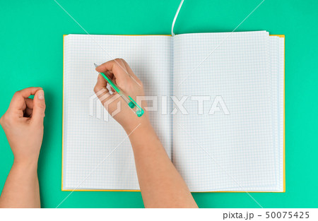 female hand holding pen, near  blank open notebook 50075425