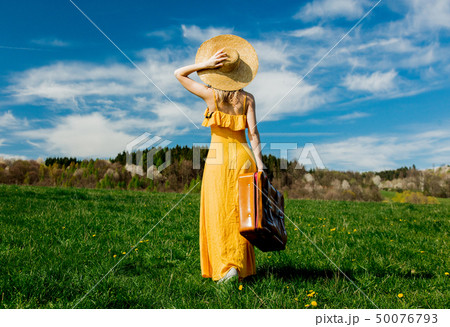 girl in yellow dress and suitcase on mountain meadow with dandelions girl in yellow dress and suitcase on mountain meadow with dandelions 50076793