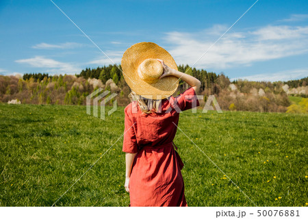Beautiful girl in red dress and hat have a carefree time on meadow 50076881