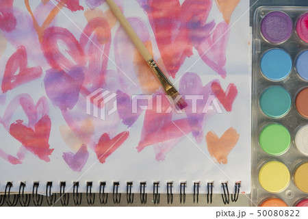 Paintbrush on watercolor painting of hearts by paints 50080822