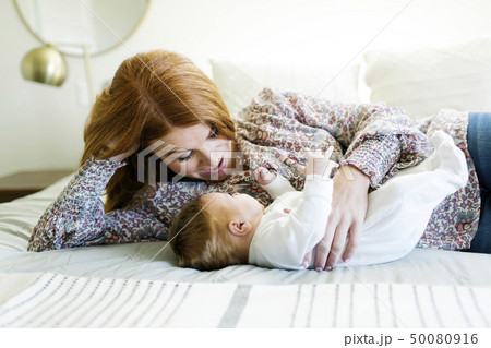 Mother lying on bed with her newborn son 50080916