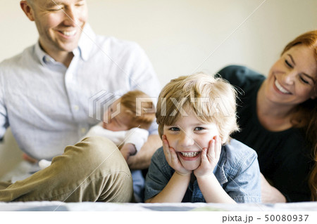Smiling family on bed 50080937
