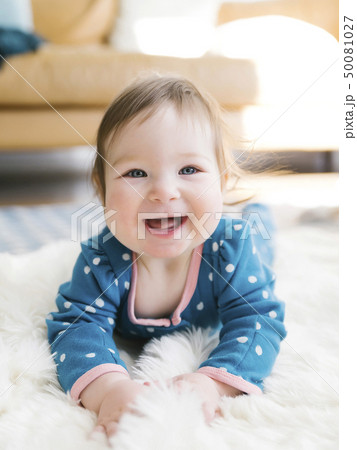 Smiling baby girl lying on rug 50081027