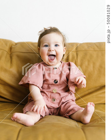 Baby girl wearing pink outfit on sofa Baby girl wearing pink outfit on sofa 50081029
