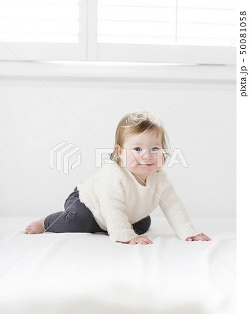 Kneeling baby girl under window 50081058